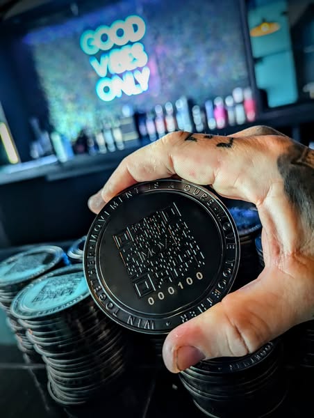 A hand holding a MOVE coin over stacks of other coins